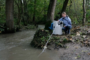 A woman monitors the water quality of a river in a forest