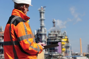 Engineer taking notes in front of a chemical plant